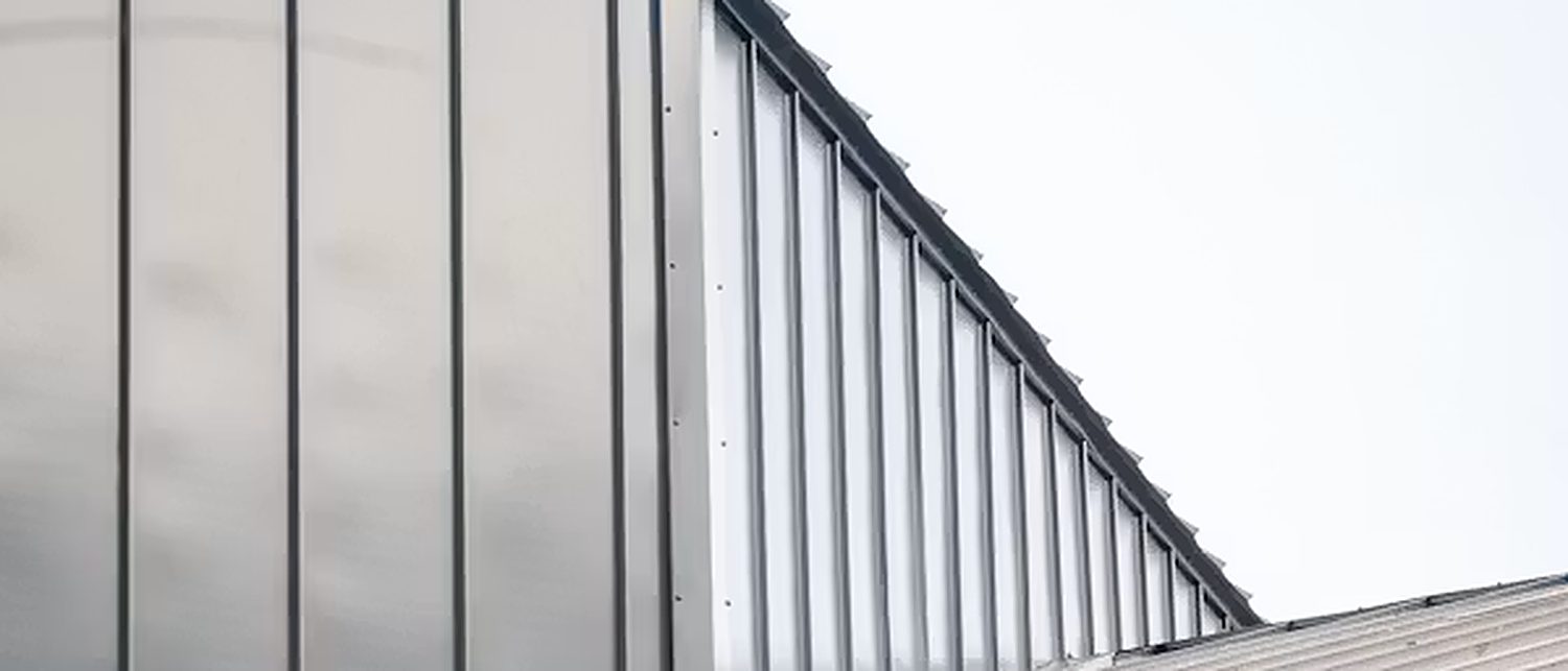 Operatives installing profiled metal roof sheeting on a large industrial building