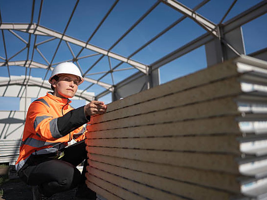 Roofing operatives installing profiled metal sheeting on a commercial roof